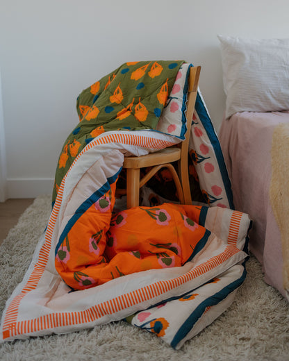 Colorful quilt with pumpkin pattern blanket draped over a chair and bed in a room.