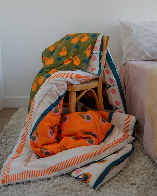 Colorful quilt with pumpkin pattern blanket draped over a chair and bed in a room.