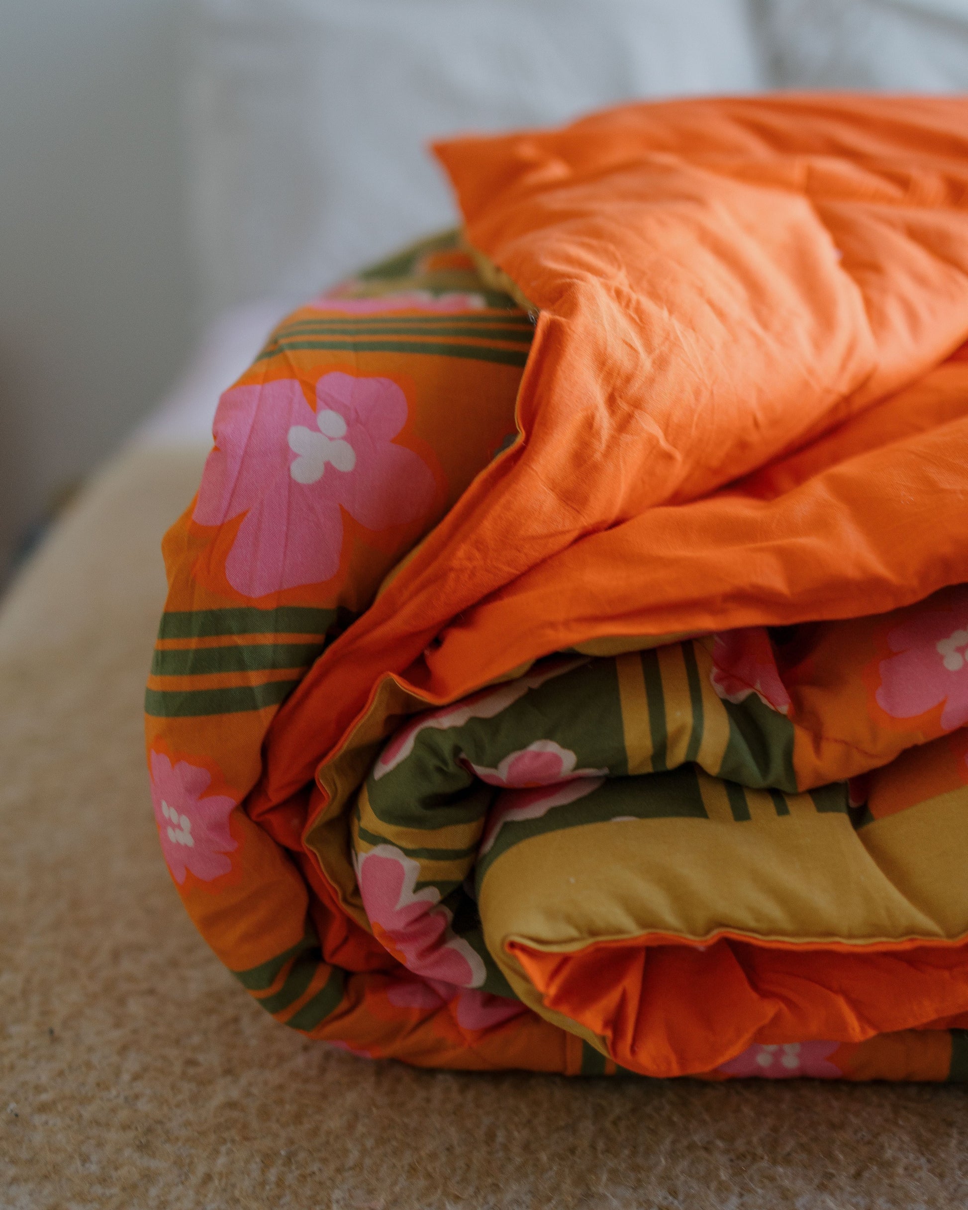 Stack of colorful quilts with floral patterns on a textured surface