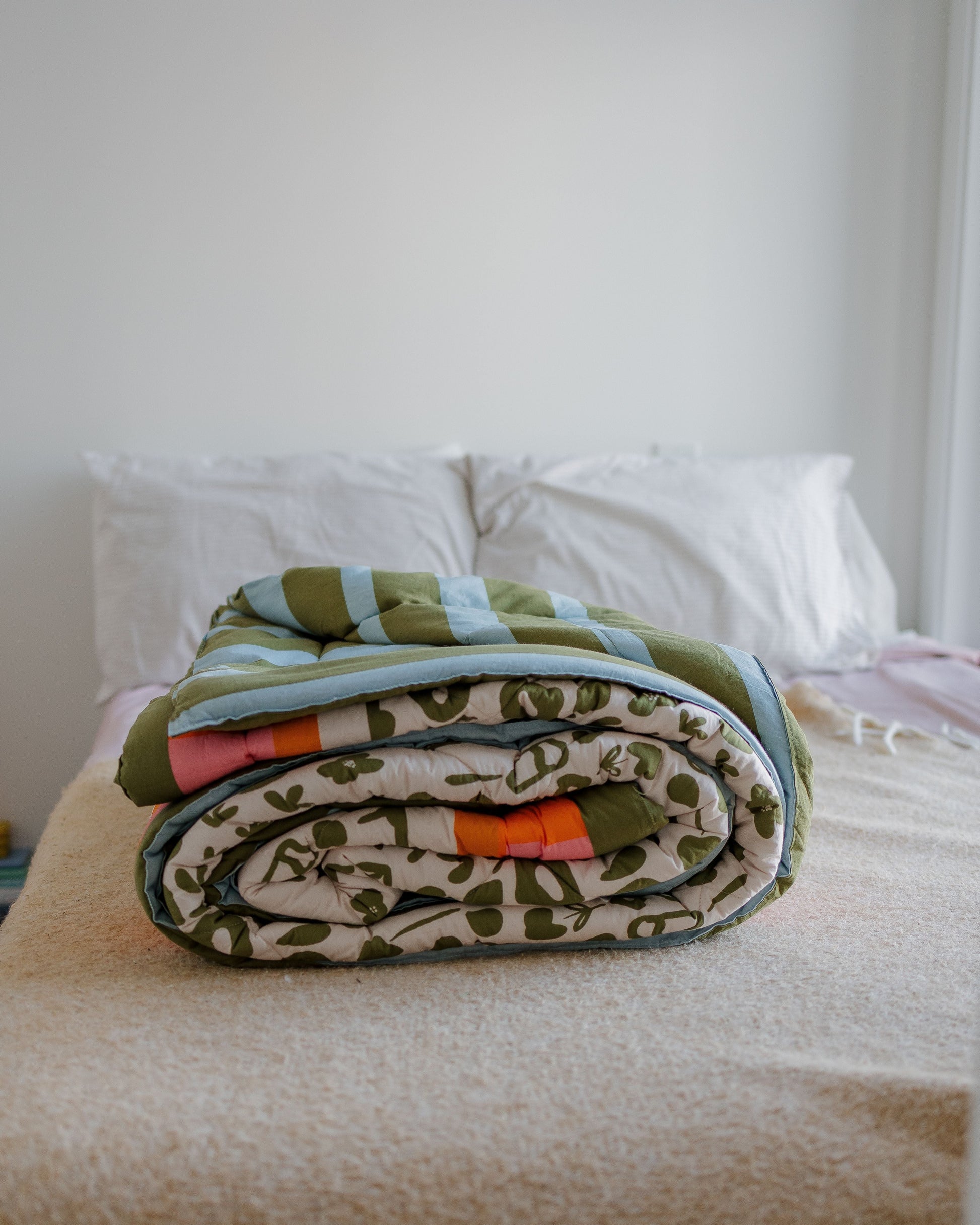 Folded blanket with a camouflage pattern on a bed