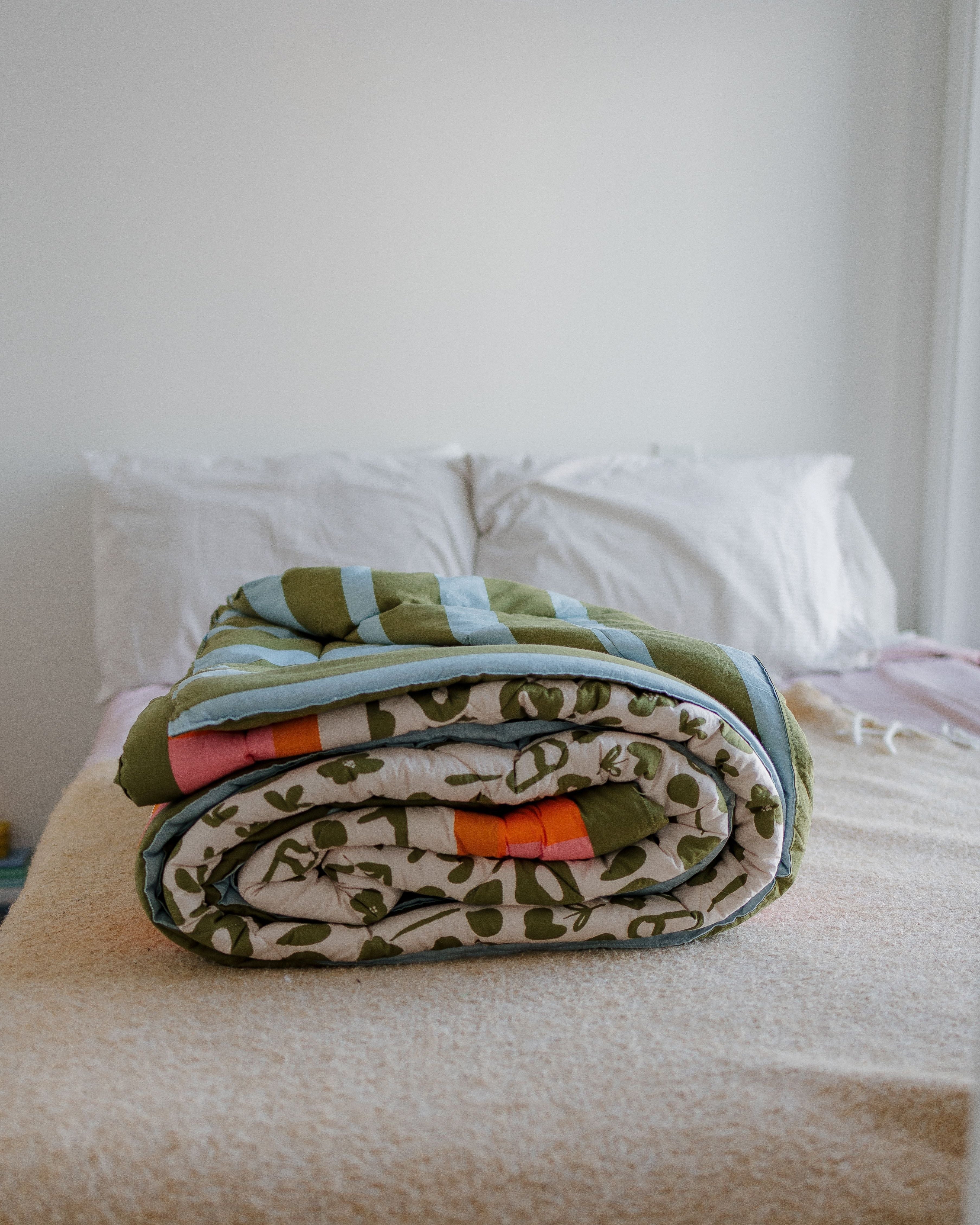 Folded blanket with a camouflage pattern on a bed