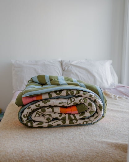 Folded blanket with a camouflage pattern on a bed